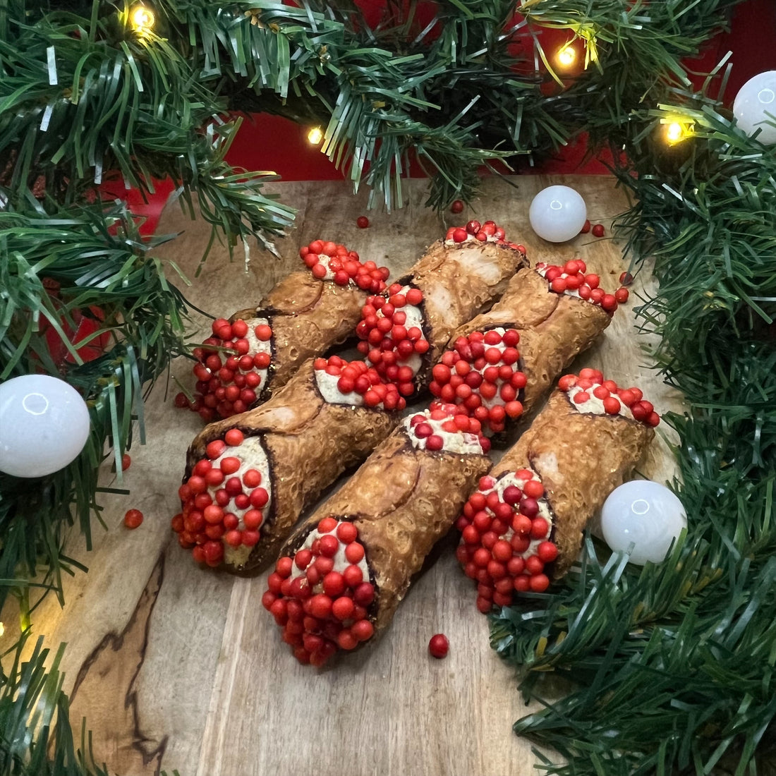 Feestelijke Cannoli Appel/Kaneel - Christmas edition van Holy Cannoli, gevuld met romige appel-kaneel crème en gedecoreerd met rode parels en eetbare gouden glitters. Perfect voor de kerst!
